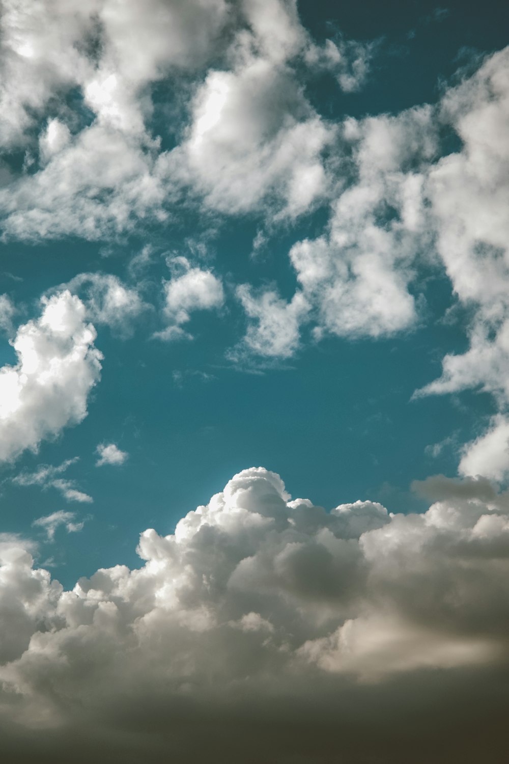 a plane flying through a cloudy blue sky