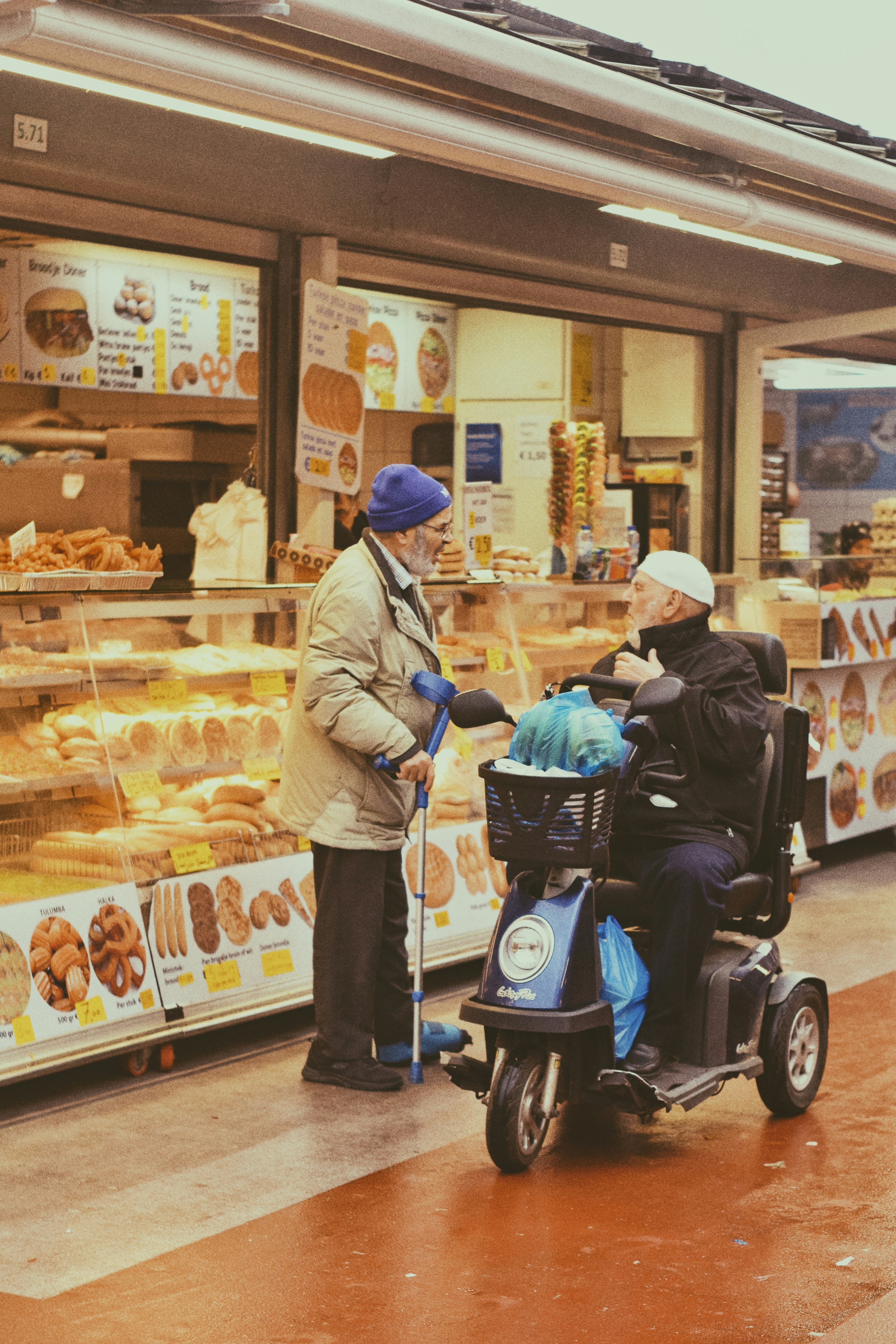 Un hombre en silla de ruedas frente a una tienda de donuts