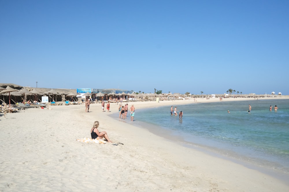 a group of people sitting on top of a sandy beach