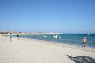 a group of people walking along a beach next to the ocean