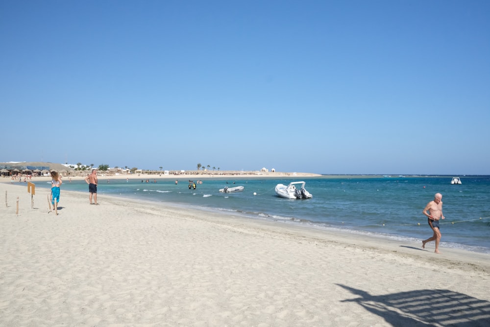 a group of people walking along a beach next to the ocean