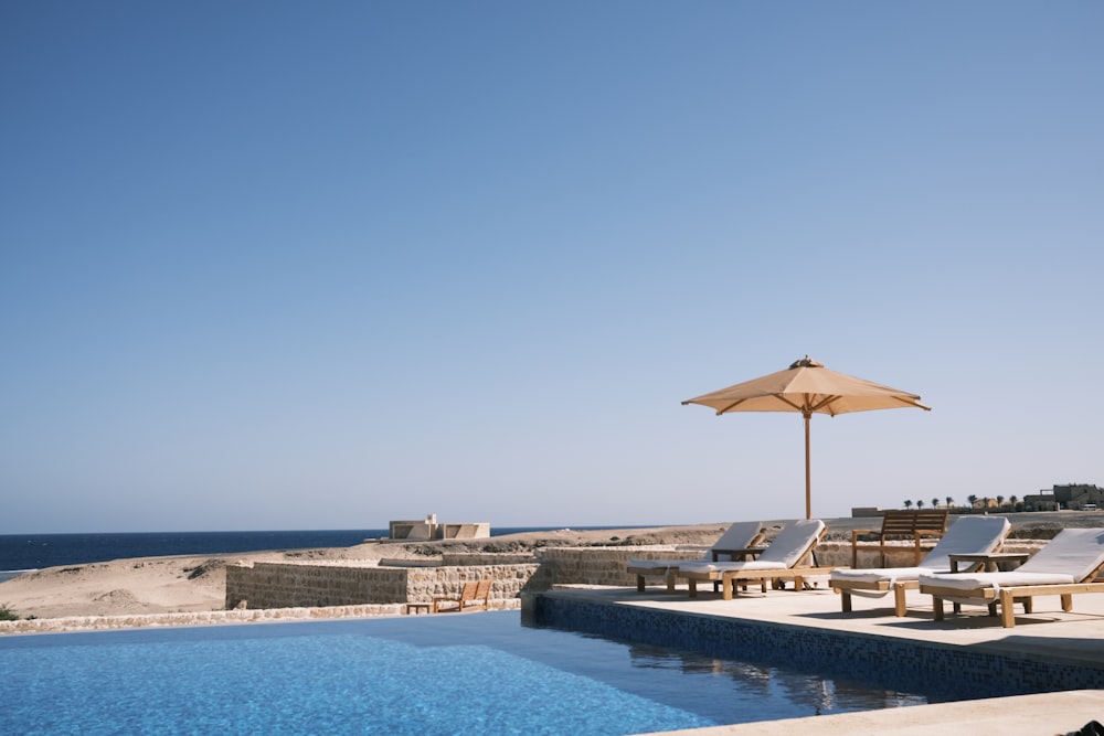 a large swimming pool with lounge chairs and an umbrella