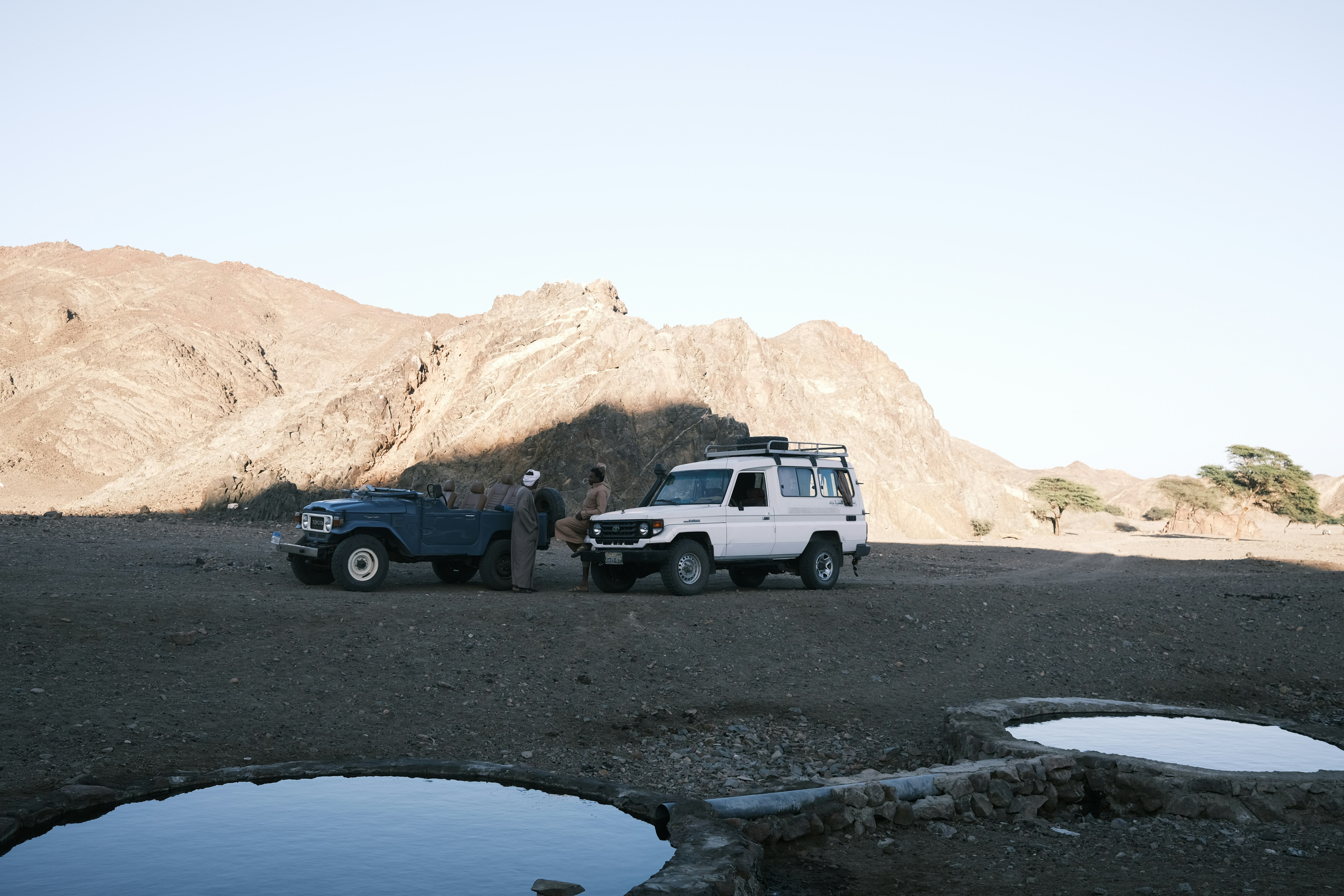 a couple of trucks parked next to a mountain
