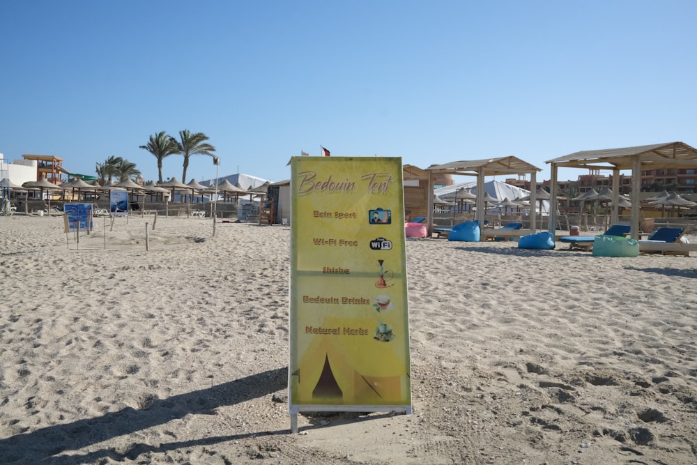 a sign on a beach with a bunch of umbrellas in the background