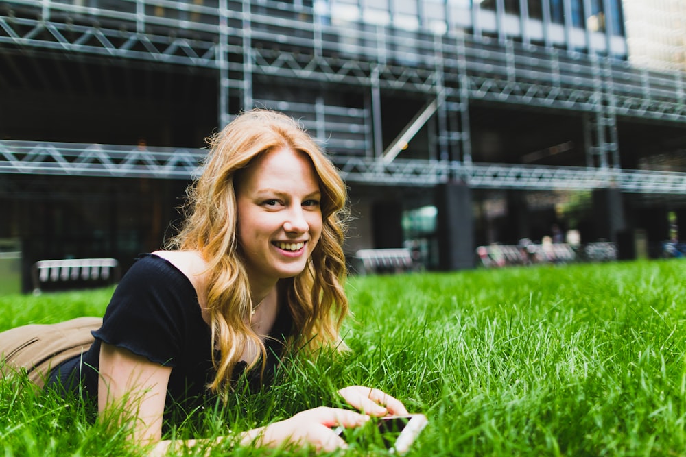 a woman laying in the grass with a cell phone