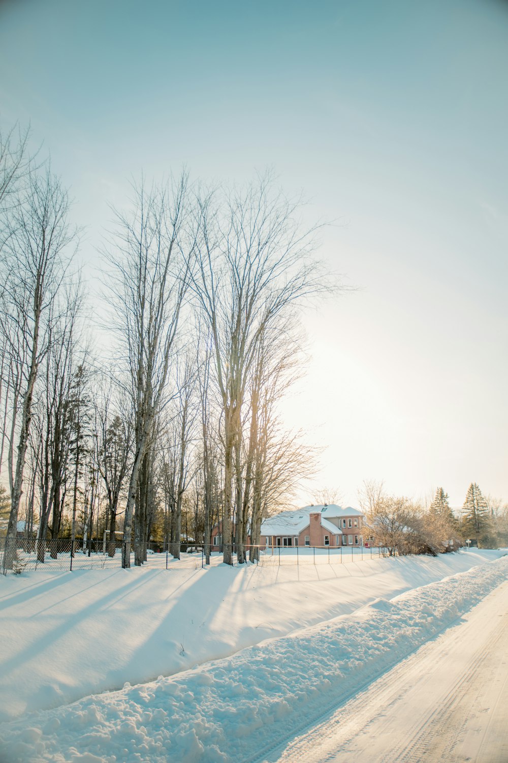 a snow covered road with a house in the background