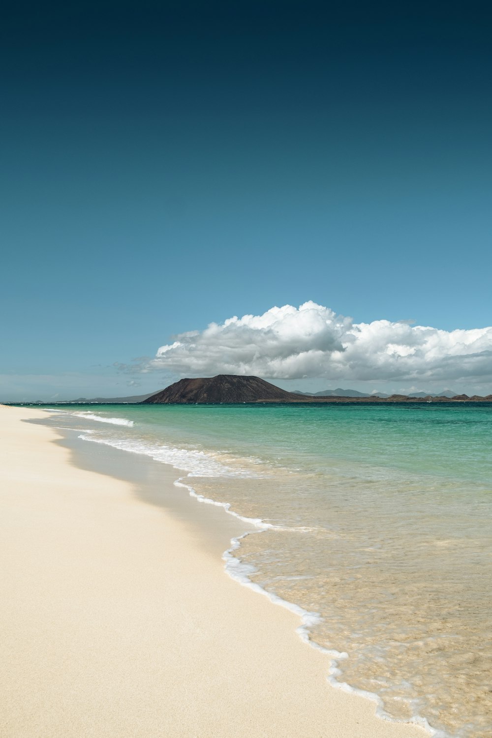 a sandy beach with a mountain in the distance