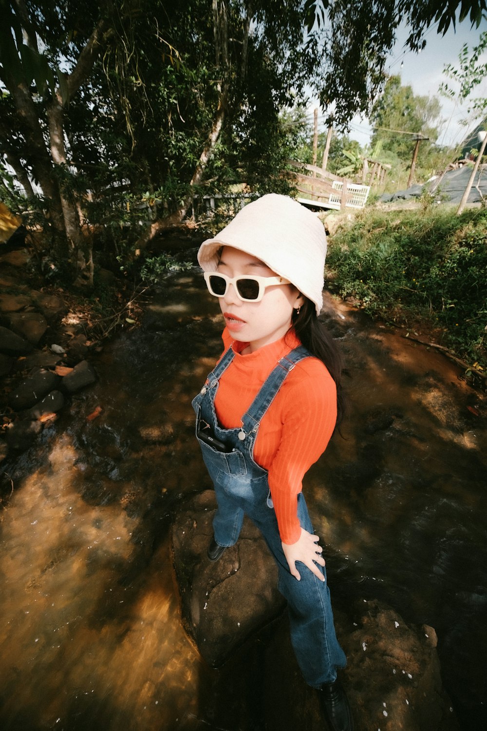 a young girl wearing overalls and a white hat