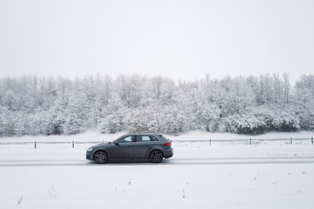 a car driving on a snowy road near a forest