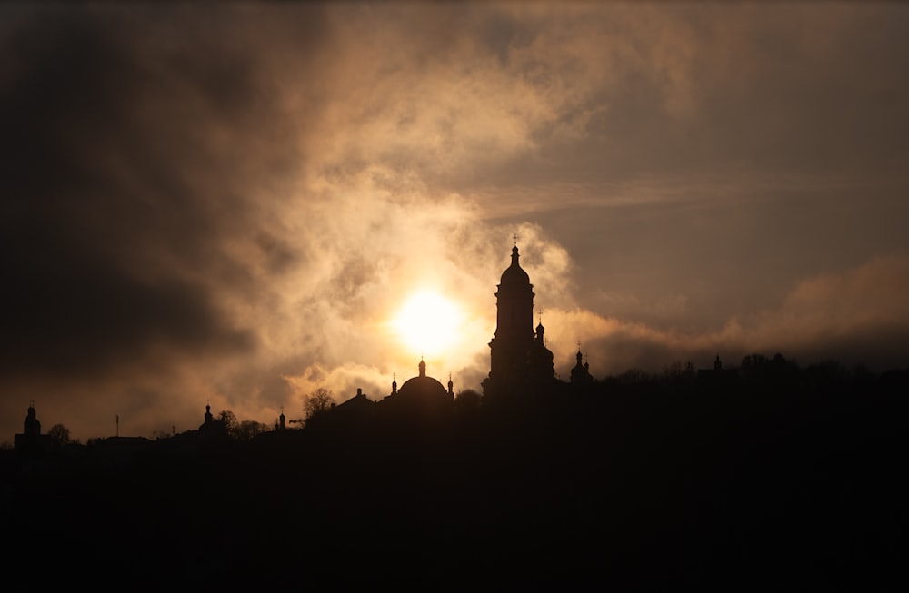 the sun is setting behind a building with a steeple