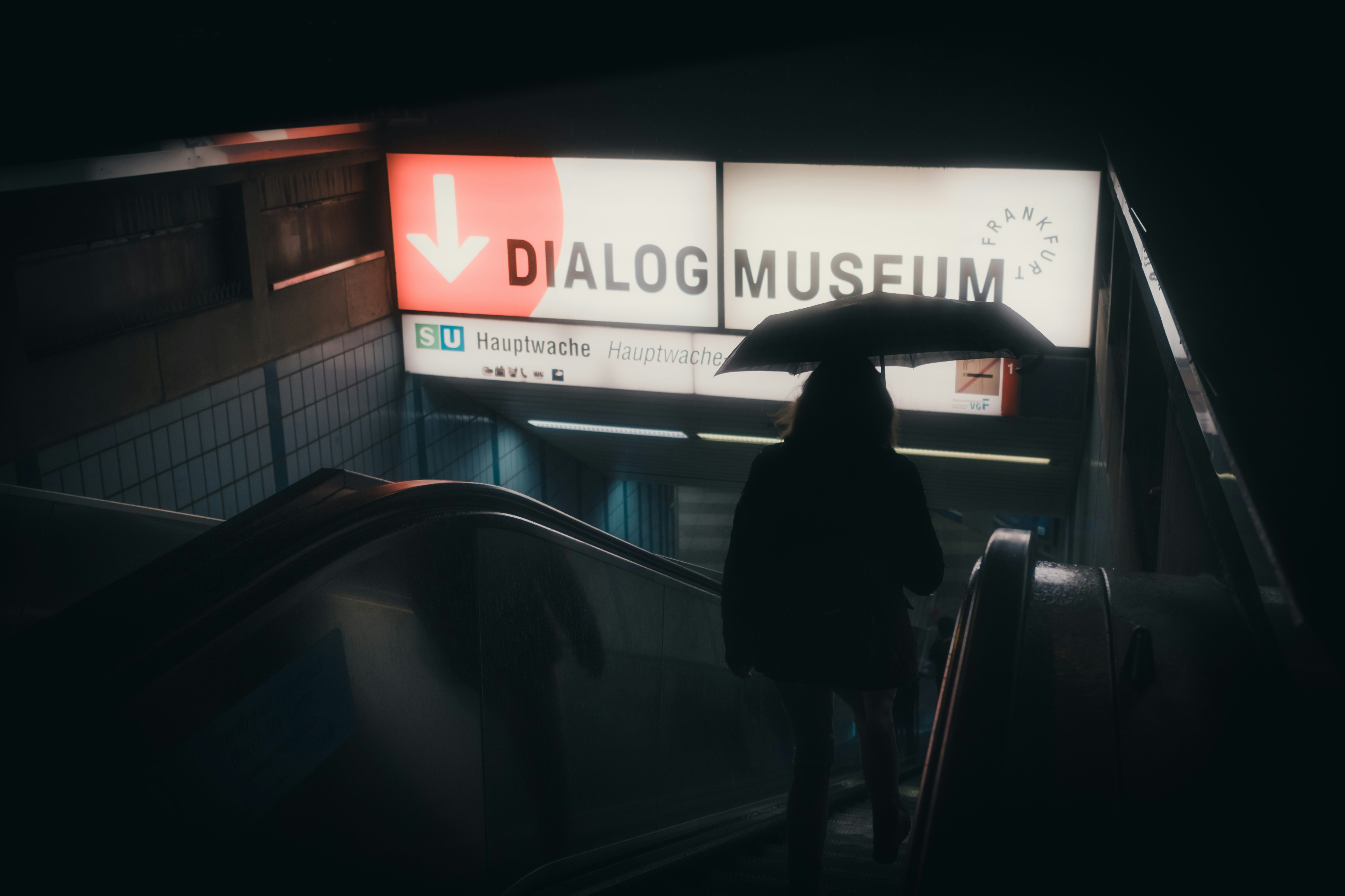 Entrance to subway station with neon sign and umbrella.