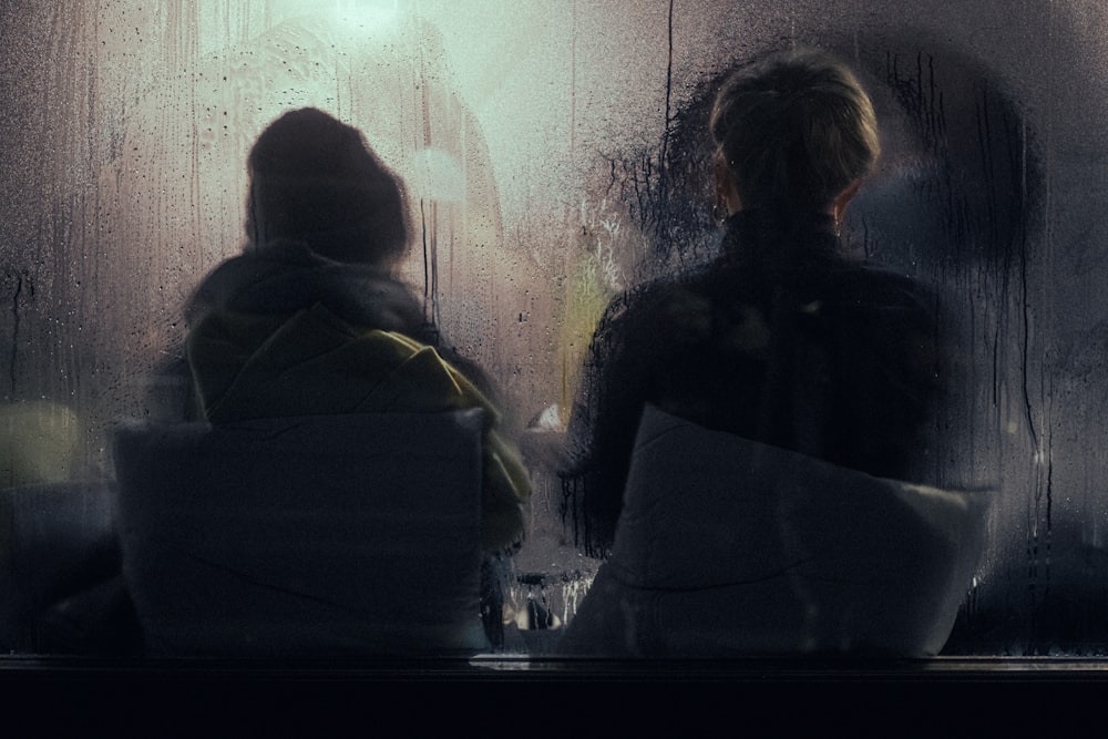 a couple of people sitting in front of a window