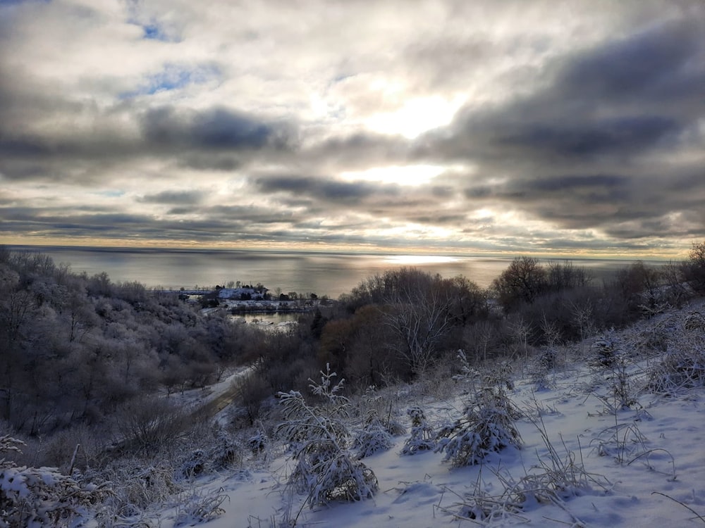 a snow covered hillside with a lake in the distance