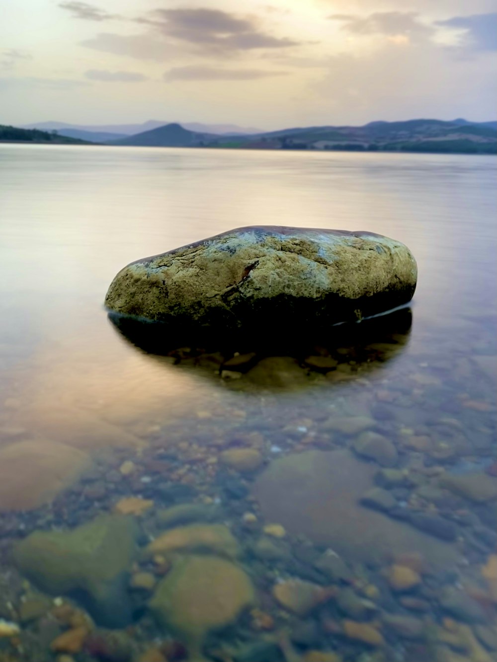 a rock sitting on top of a body of water