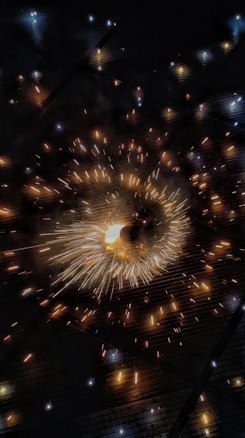 A dynamic display of golden and white sparks radiating outward against a dark backdrop, creating a dazzling effect reminiscent of fireworks or a light show.
