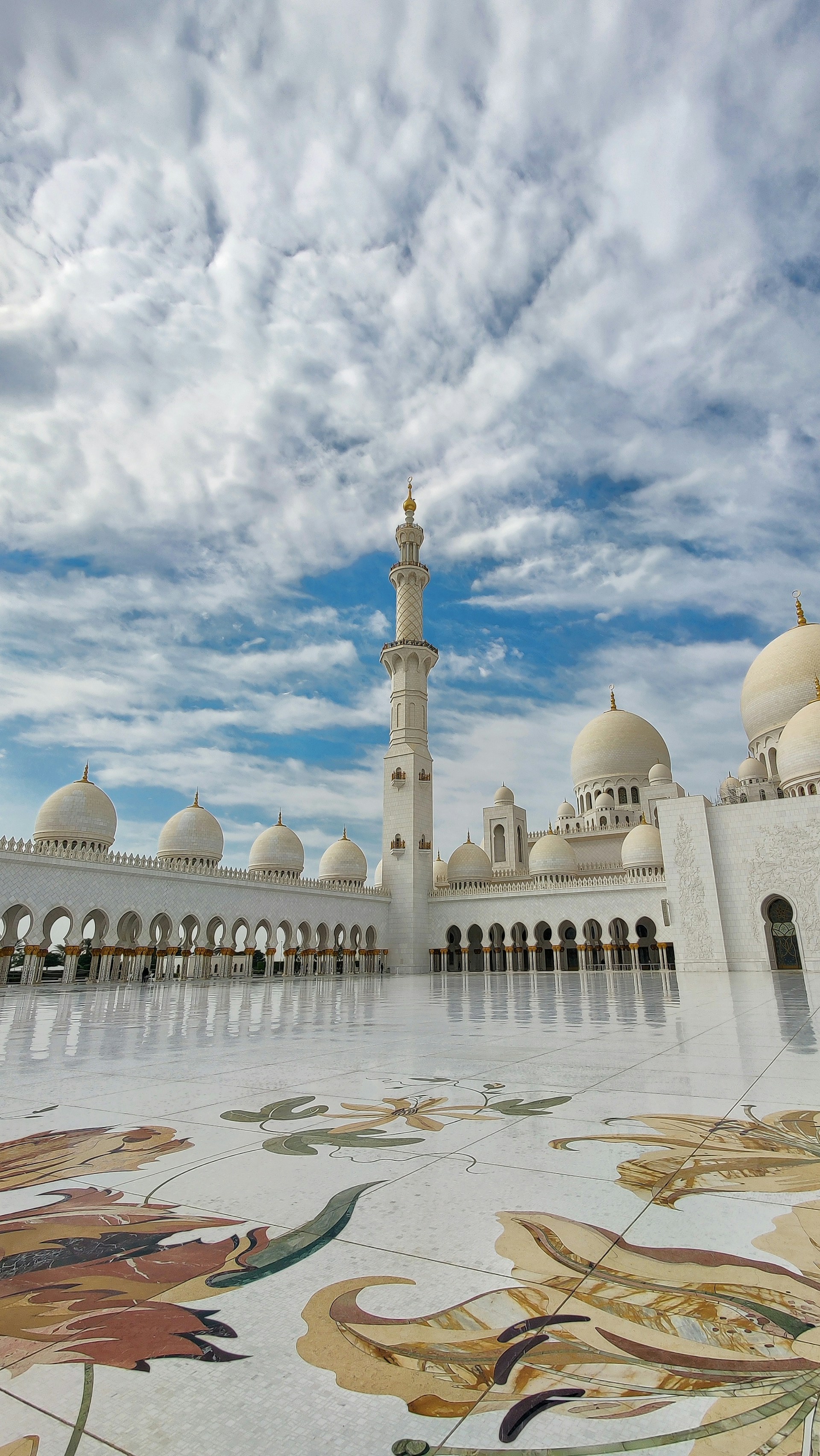 The majestic green dome of Masjid an-Nabawi in Madinah, framed by a clear blue sky and the peaceful courtyard bustling with visitors.