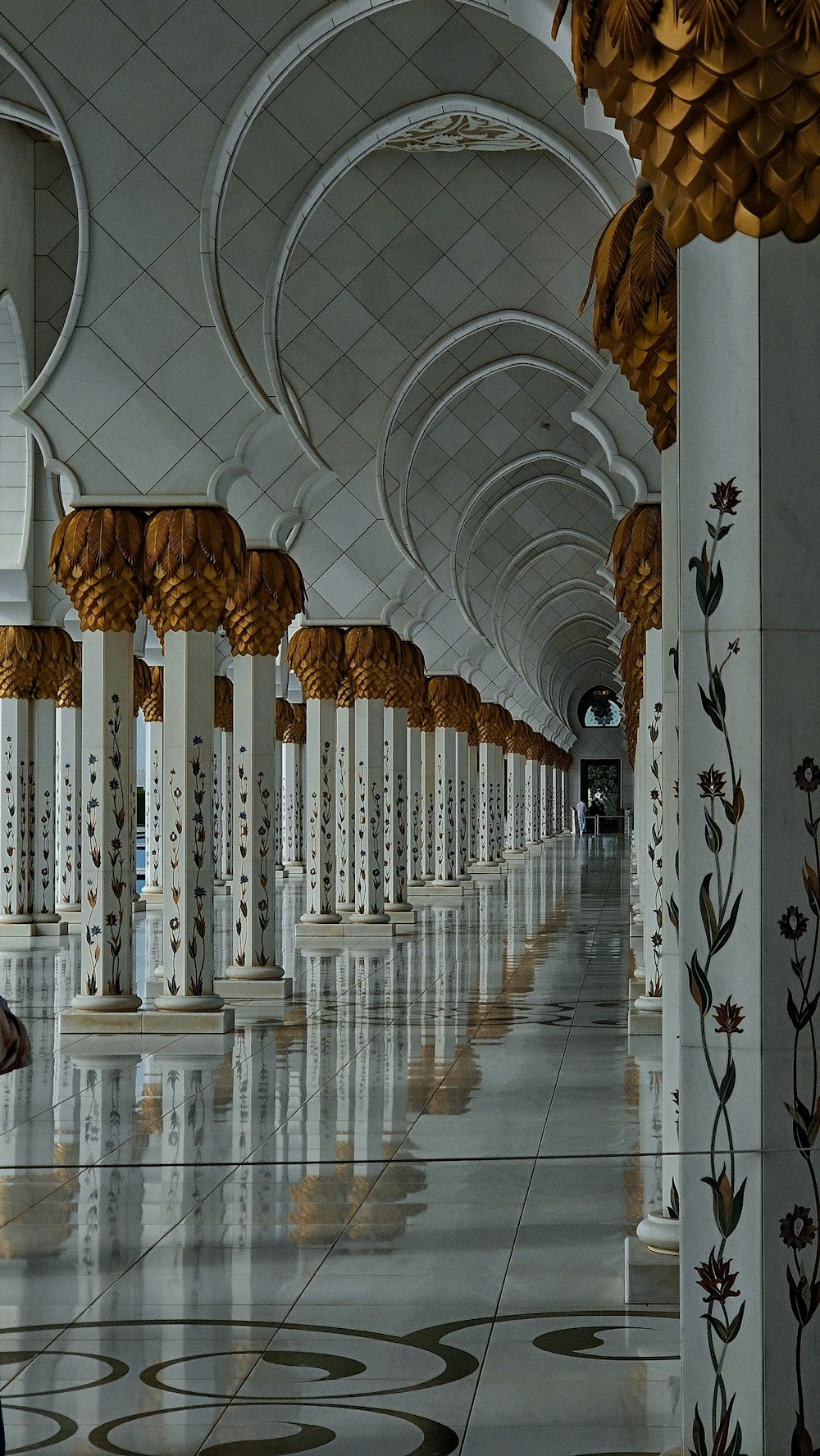 a long hallway with white columns and gold decorations