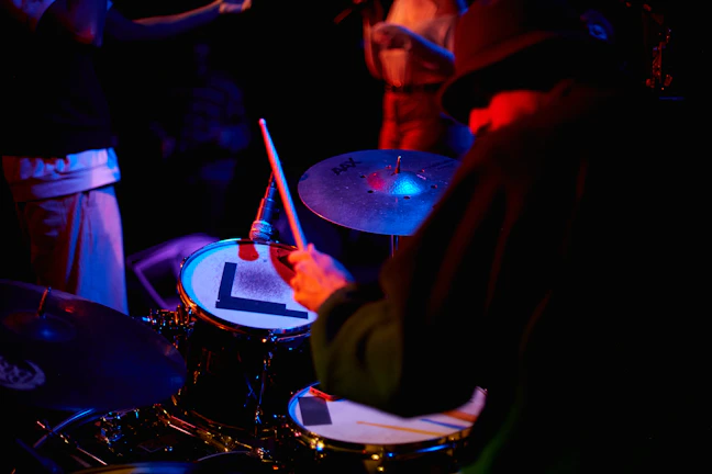 A candid moment of the drummer tuning his kit, focused and ready to play.