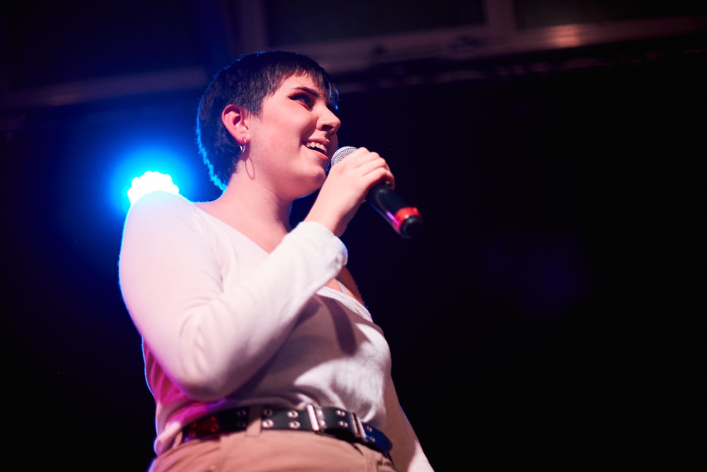 Una mujer cantando en un micrófono en el escenario