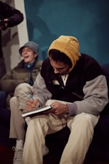 a man sitting on a couch writing on a book