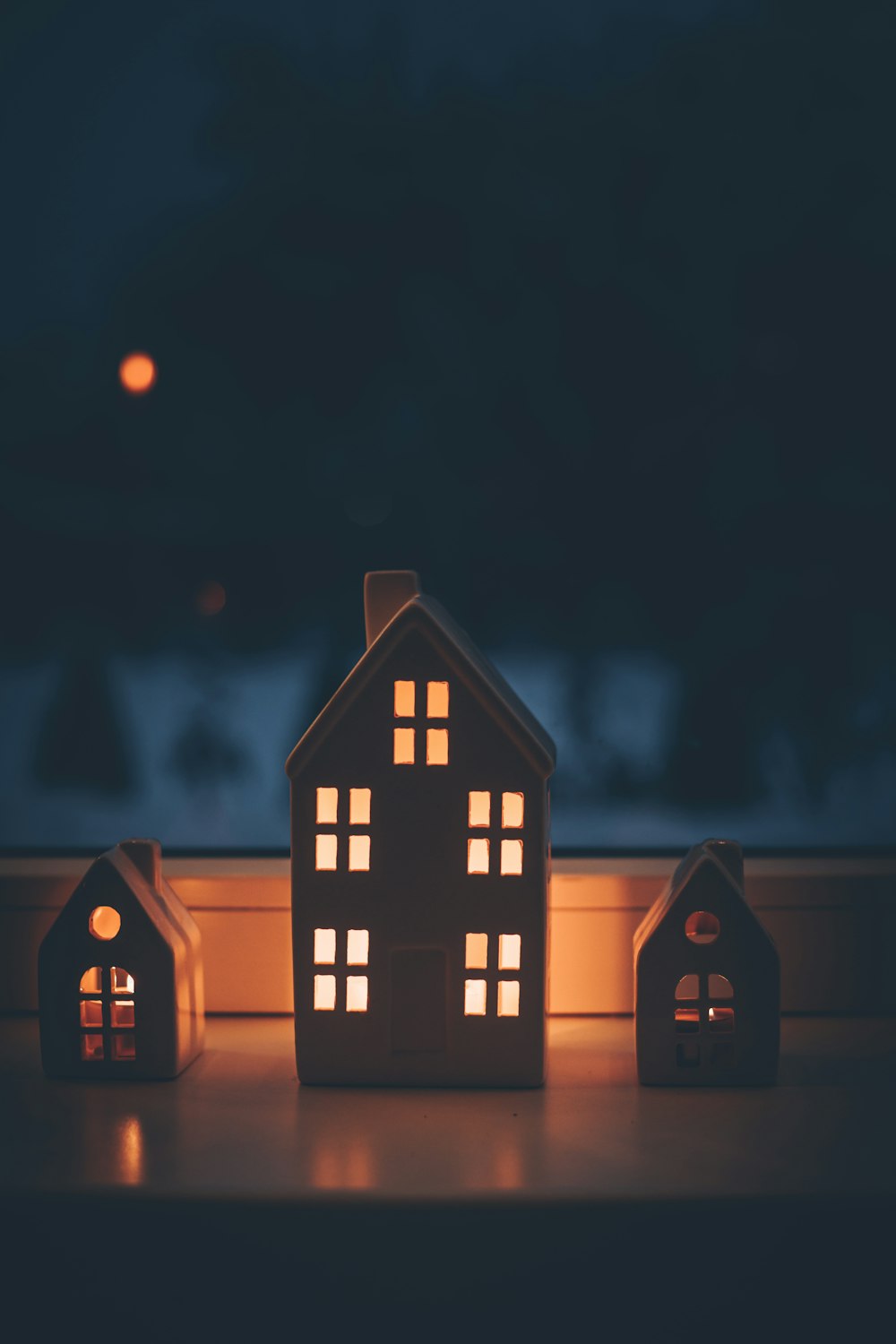 a lit up house sitting next to a window sill