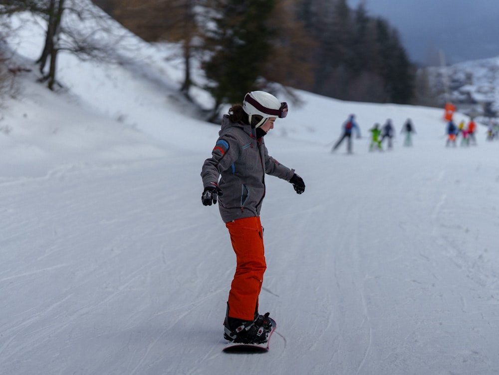 a person riding a snowboard down a snow covered slope