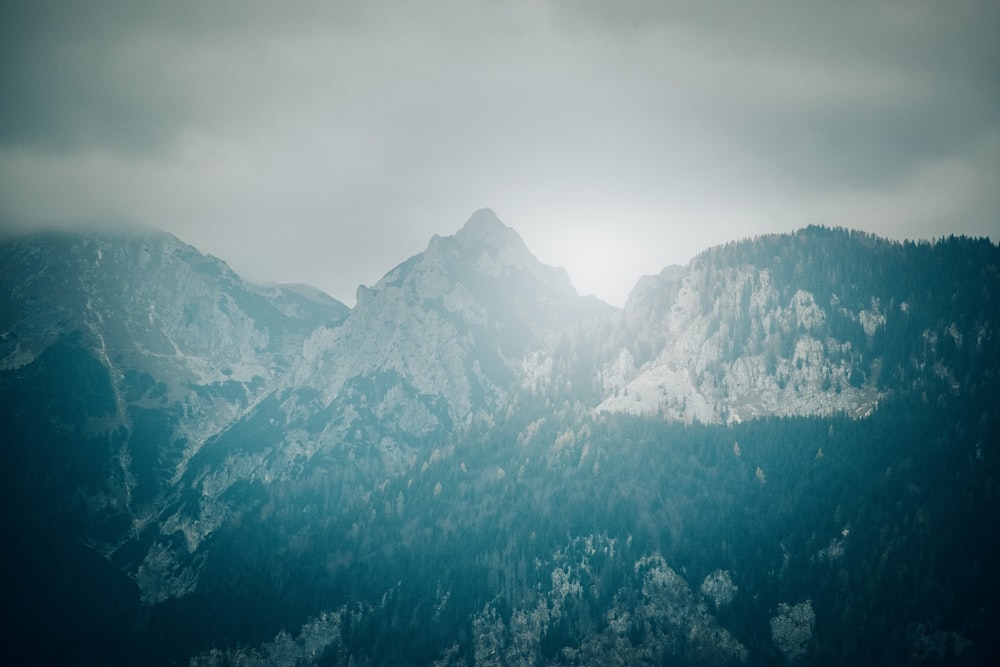 a mountain range covered in snow under a cloudy sky