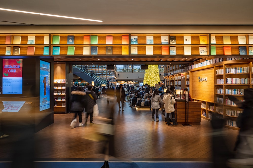 a group of people walking through a library filled with books