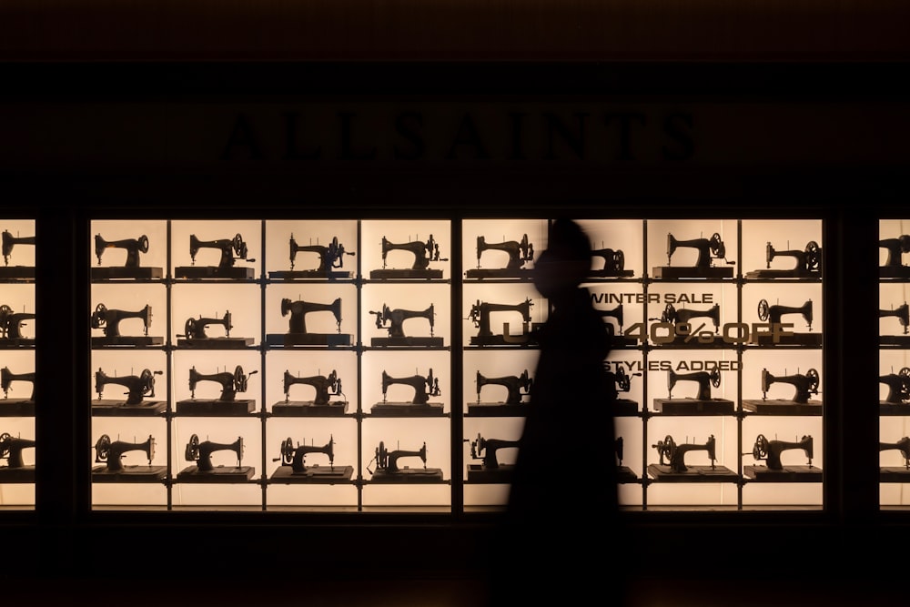 a silhouette of a person standing in front of a display of sewing machines