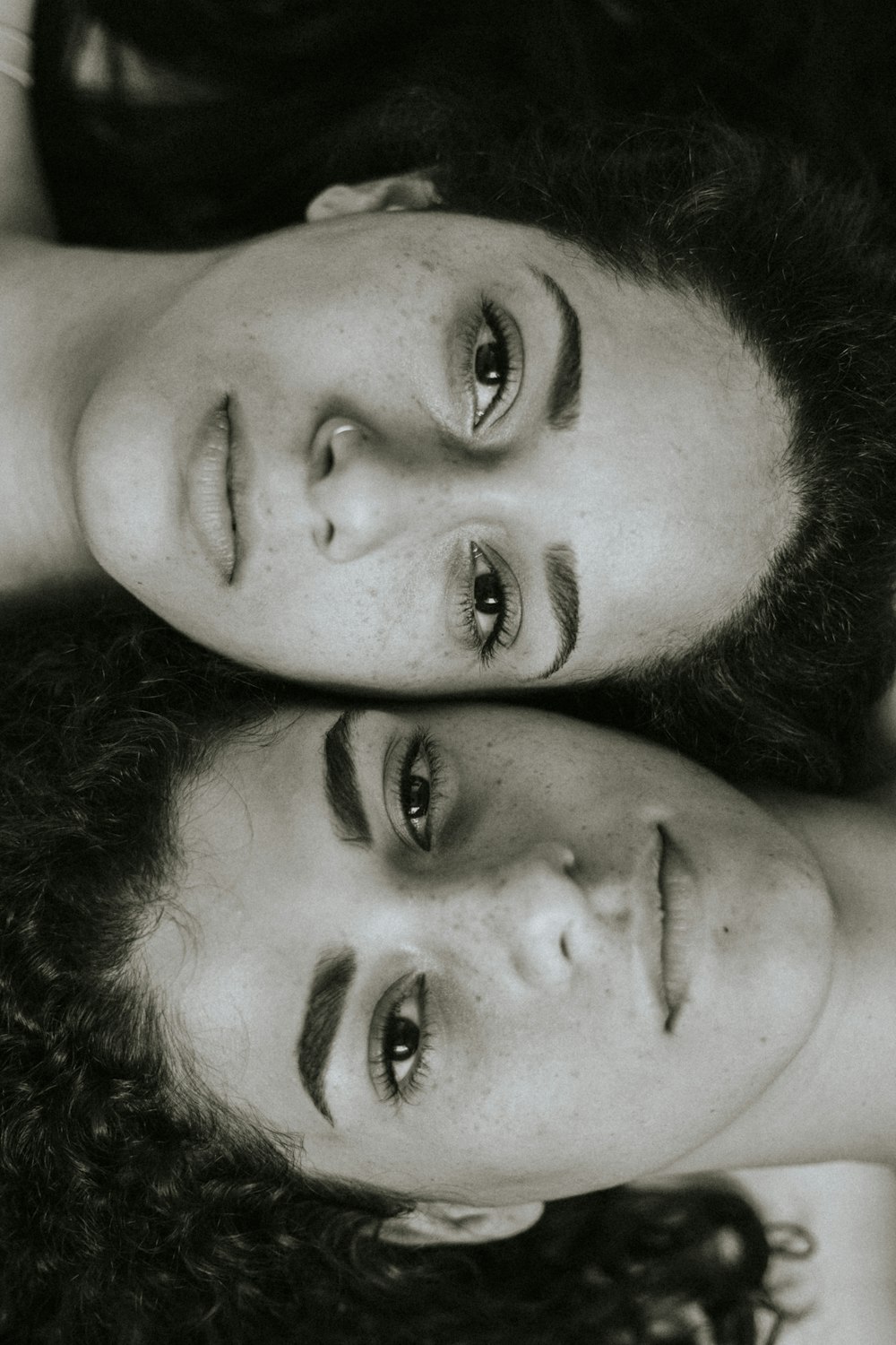 two women are laying down with their heads together