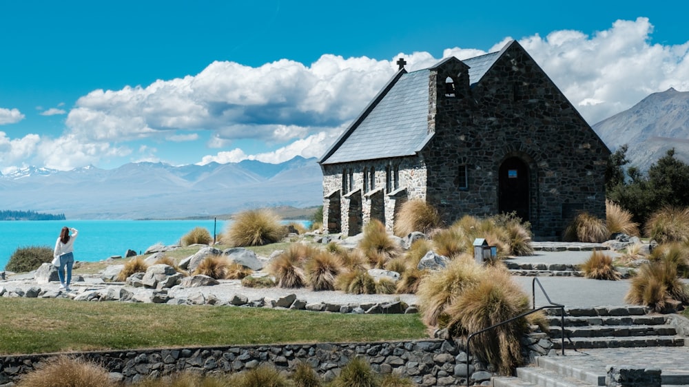 a woman standing in front of a church next to a body of water