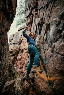 a woman climbing up the side of a mountain