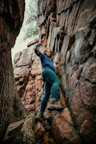 a woman climbing up the side of a mountain