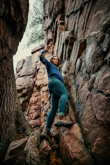 a woman climbing up the side of a mountain
