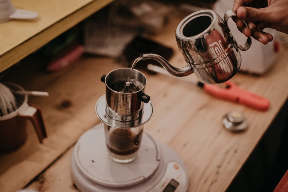 a person pours a cup of coffee from a coffee maker