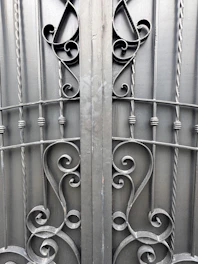 Close-up of a handcrafted steel gate featuring elegant scroll patterns and a matte black finish.