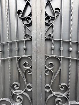 Close-up of a handcrafted steel gate featuring elegant scroll patterns and a matte black finish.