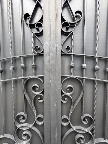 Finished handcrafted iron gate with intricate scrollwork displayed outdoors.