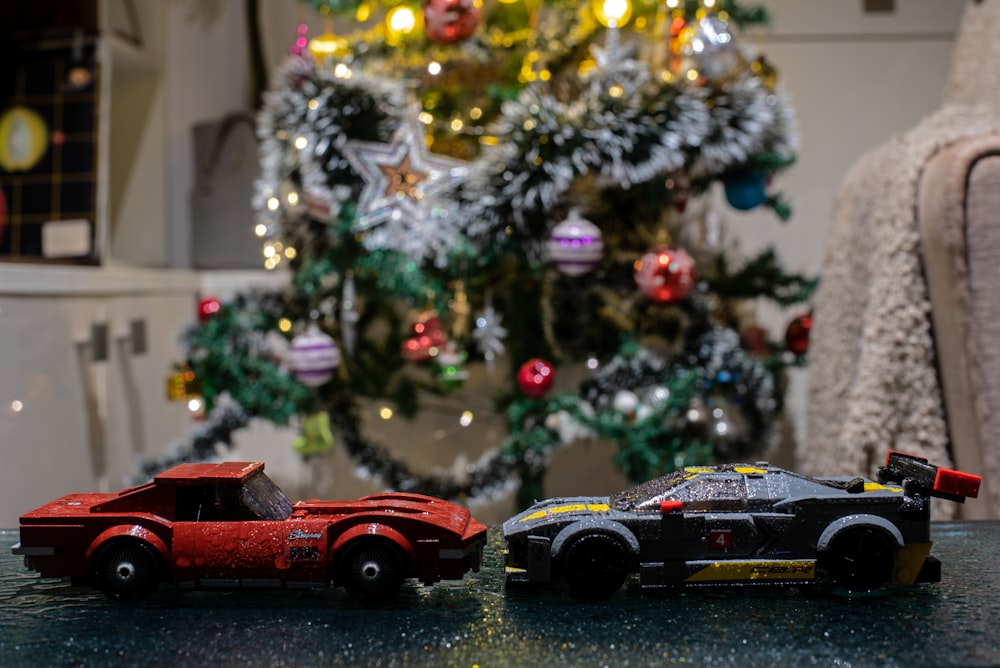 two toy cars sitting on a table in front of a christmas tree