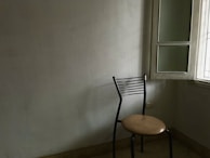 A simple, empty chair by a window with soft morning light, evoking solitude and introspection.