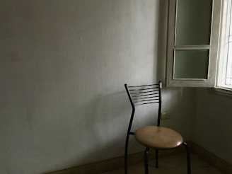 A simple, empty chair by a window with soft morning light, evoking solitude and introspection.