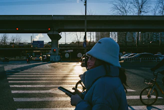 A candid moment of a person adjusting their Lumina Apparel jacket while waiting at a city crosswalk.