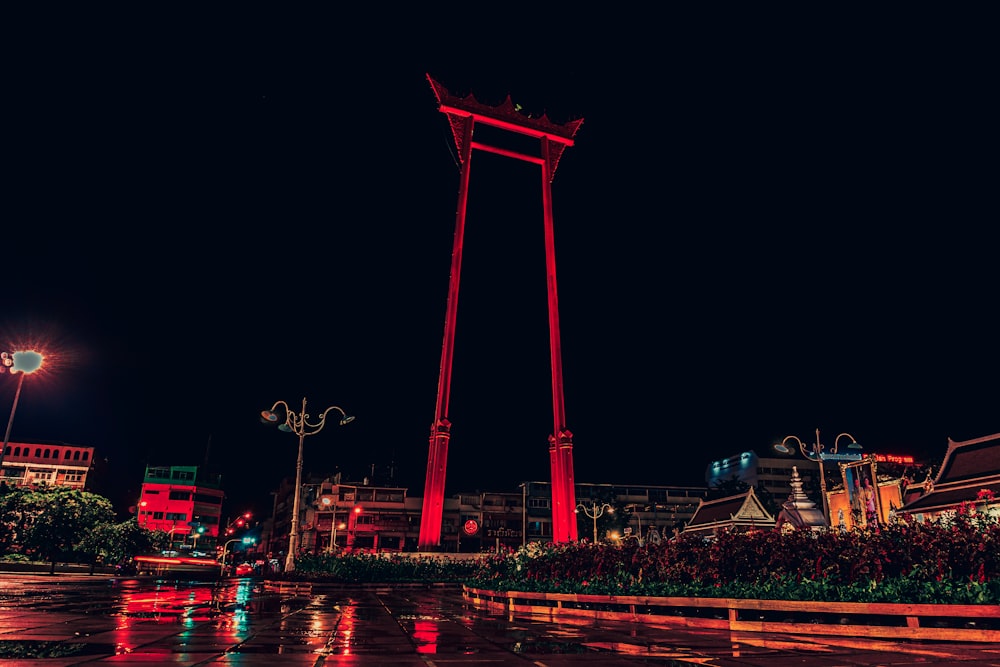 a red clock tower in the middle of a city at night