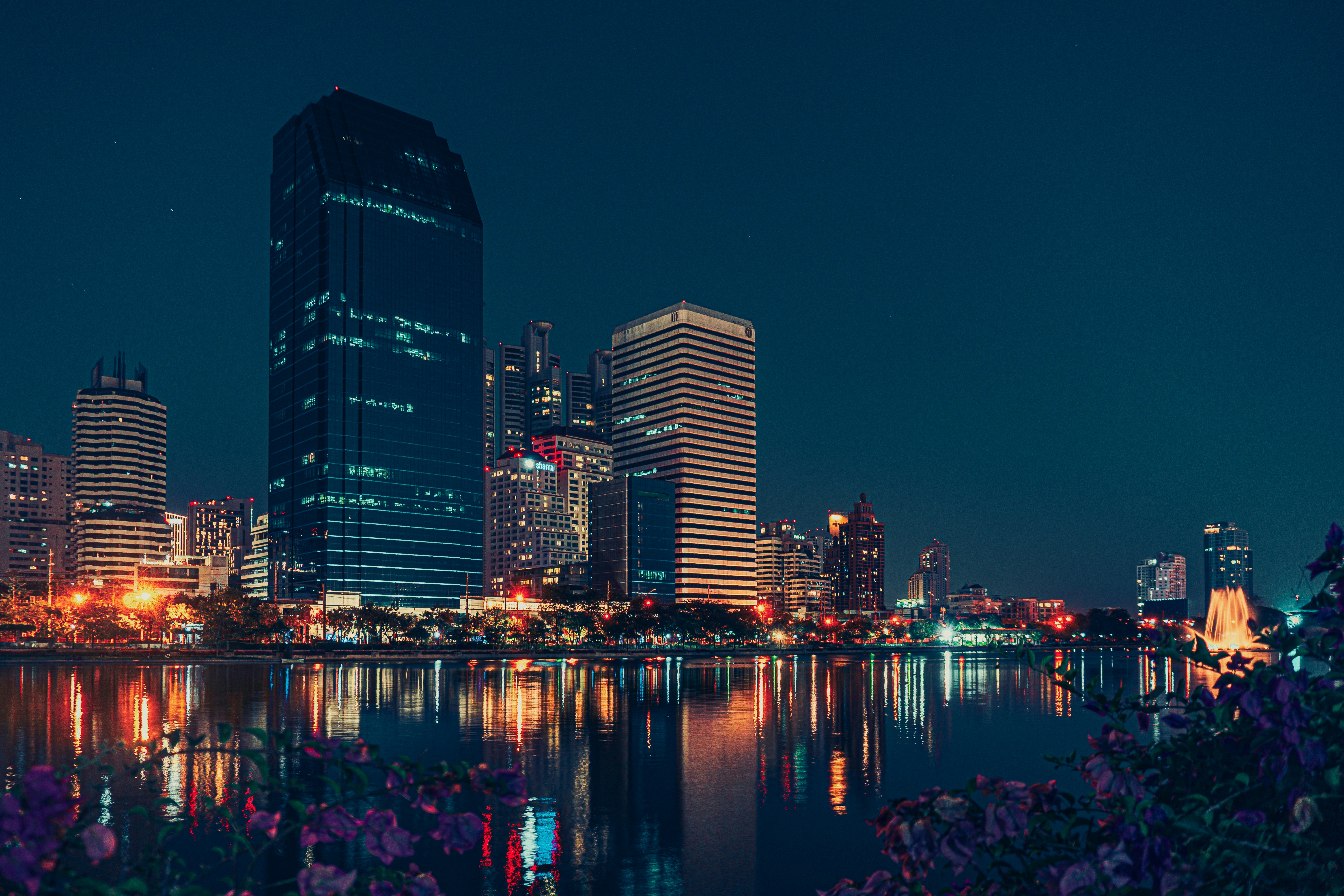 a city skyline at night with a lake in the foreground