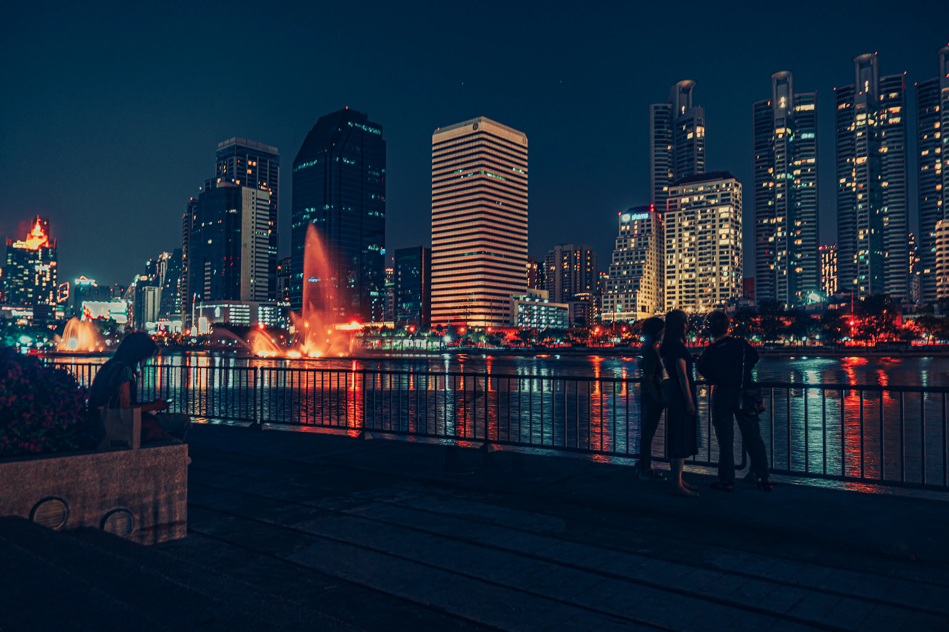 a couple of people standing on top of a pier next to a body of water