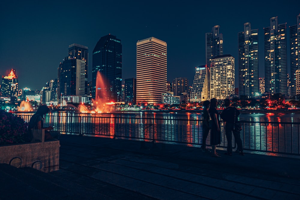 a couple of people standing on top of a pier next to a body of water