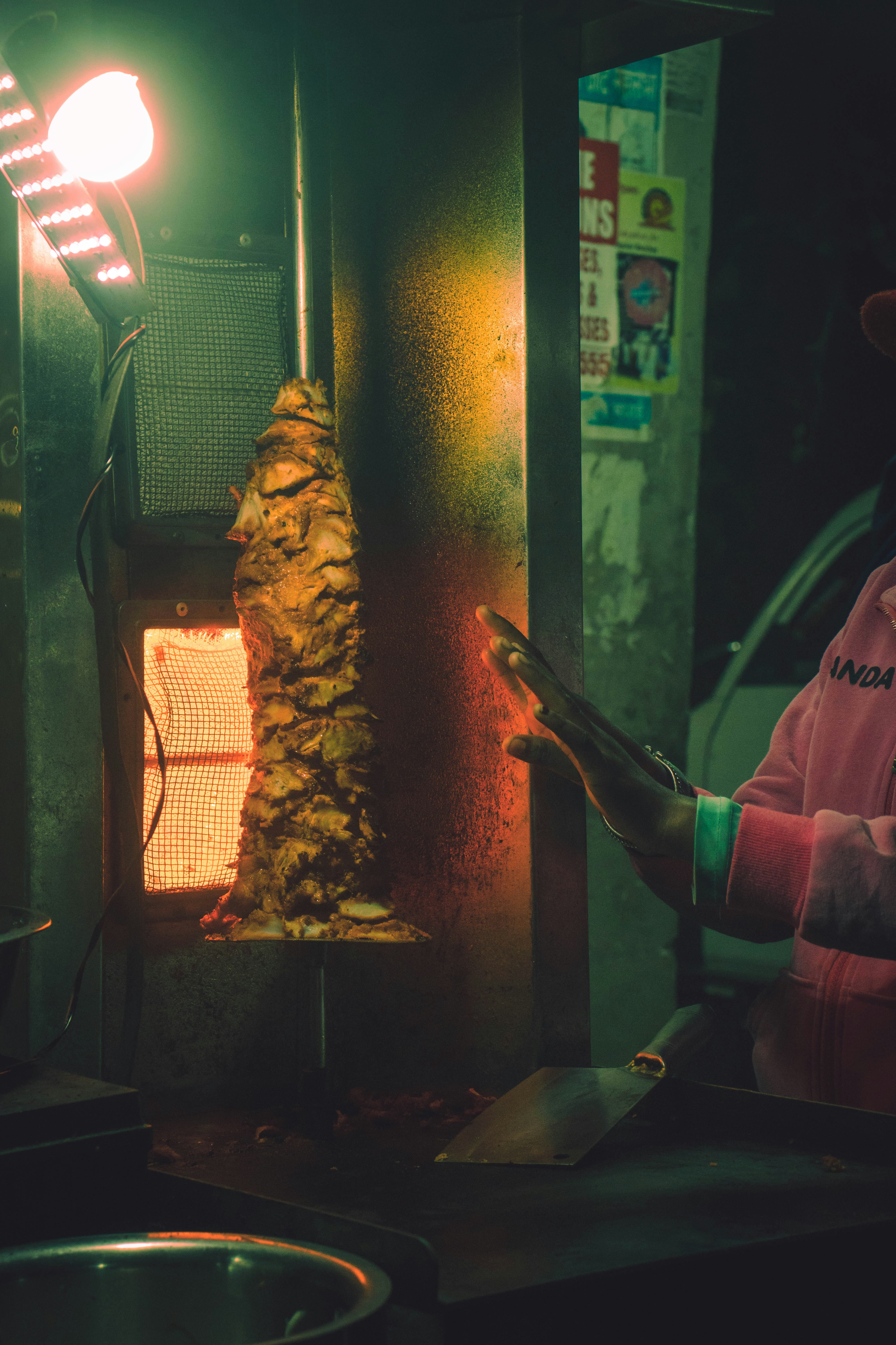 Shawarma meat on rotating spit, golden brown, steam rising, dim kitchen light