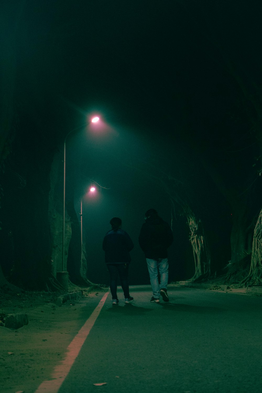 a couple of people walking down a street at night