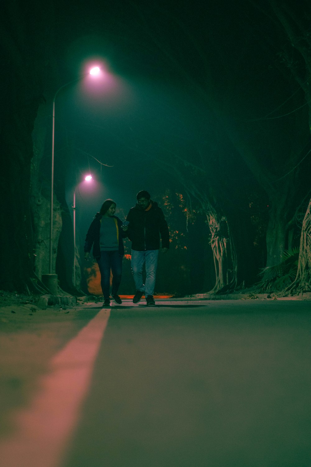 a man and a woman walking down a street at night