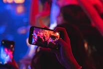 Close-up of a singer engaging with fans through a smartphone in a moody, artistic setting.